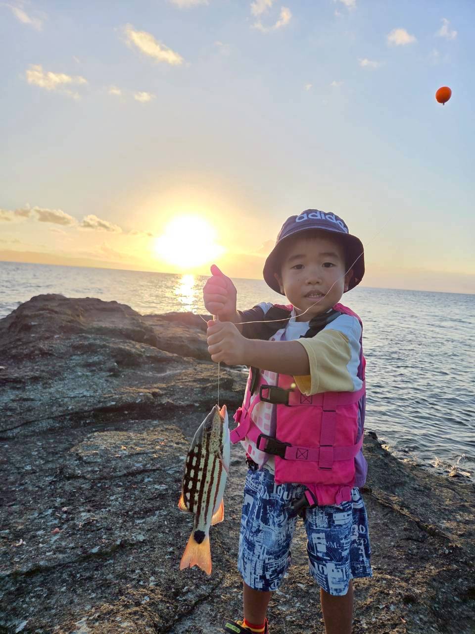 石垣島ショア釣り体験 サンセットの中で魚を釣る少年